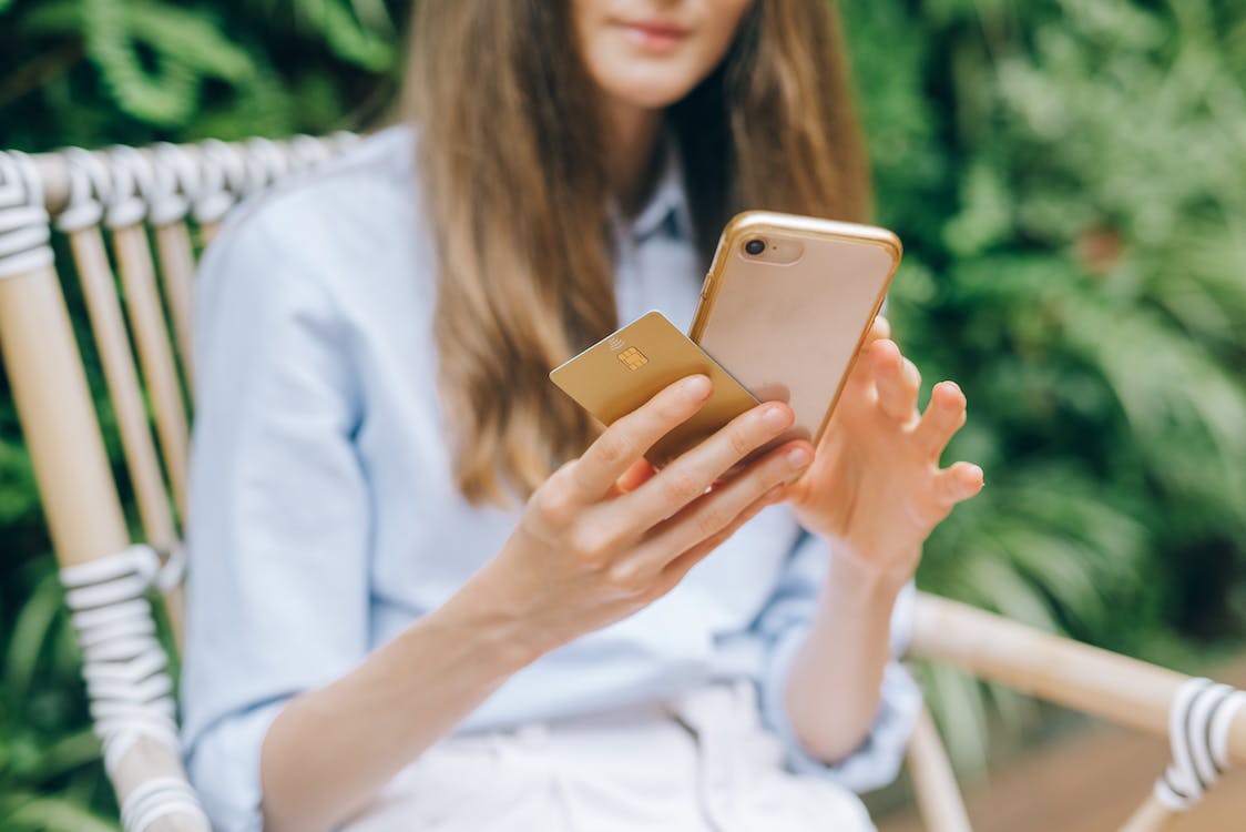 a woman using her smartphone while holding a credit card