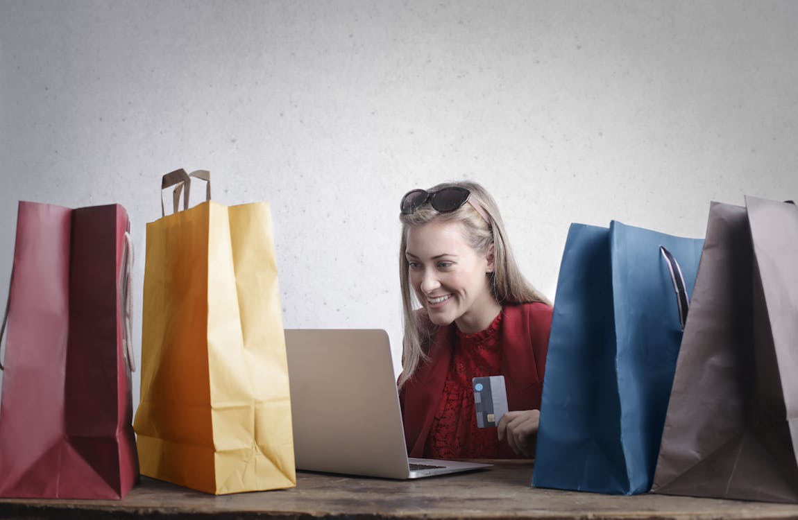 A person with shopping bags using a laptop, holding their credit card