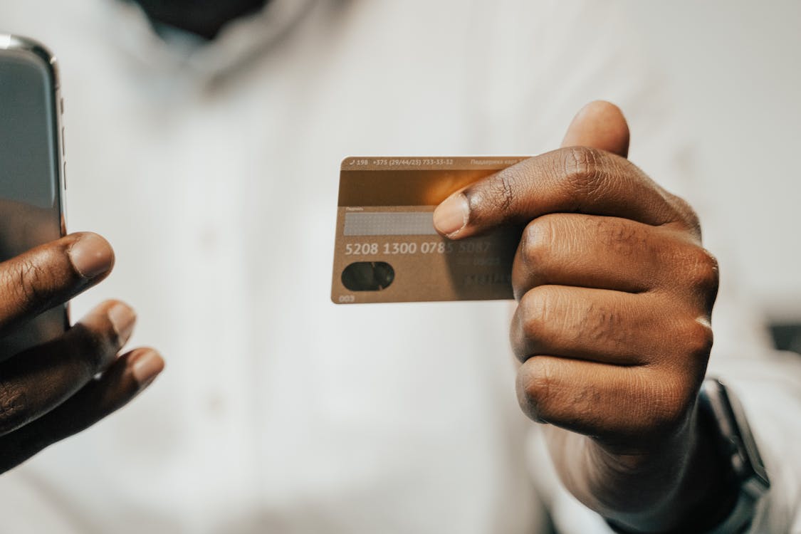 Cropped photo of a person holding their cellphone and gold credit card